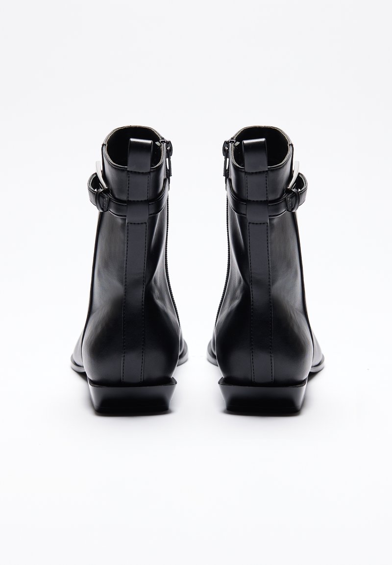Zwarte leren enkellaarsjes met een slank ontwerp, zijritsen en een lage blokhak. Accenten zijn verstelbare banden bij de enkel.