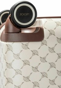 Biała walizka z teksturowanym, tłoczonym wzorem w kształcie wachlarzy. Brązowe akcenty i kółka z czarnymi obręczami z logo "JOOP!".