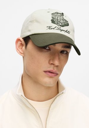 Gorra beige con visera verde, presenta un edificio bordado y el texto "Karl Lagerfeld". Fabricada con tela de textura suave.