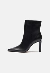 Bottine en cuir noir avec un bout pointu et un talon haut mince, caractérisée par une texture lisse et un design épuré.