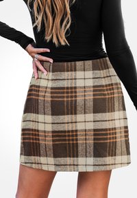 Mini gonna a quadri marrone e beige in un tessuto morbido con un design strutturato, caratterizzata da una vita alta e sottili accenti arancioni nel motivo.
