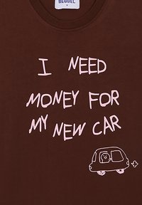Camiseta marrón con cuello redondo que presenta un texto escrito a mano en rosa: "NECESITO DINERO PARA MI COCHE NUEVO" y una representación simple de un coche.