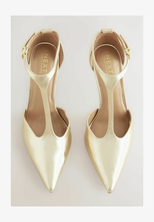 Goldene metallic High Heels mit spitzen Zehen, offenen Seiten und einem Knöchelriemen mit Schnalle. Glatte Oberfläche und minimalistisches Design.