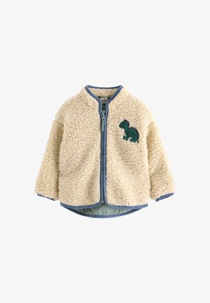 Kermanvärinen vauvan fleece-takki sinisellä reunuksella ja vihreällä dinosauruspainatuksella vasemmassa rinnassa, edessä vetoketjusulku.