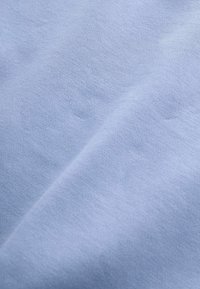 Tissu bleu clair avec une texture lisse et douce et des plis délicats, montrant un tricot fin et un léger ombrage.