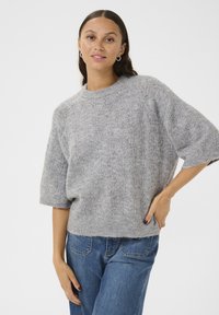 Grijze gebreide trui met een textuurpatroon, korte mouwen en een ronde halslijn, gecombineerd met blauwe denim jeans. Zachte stofuitstraling.