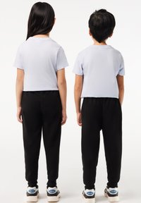 Gekürzte hellblaue T-Shirts kombiniert mit schwarzen Jogginghosen. Beide Outfits zeichnen sich durch eine lässige Passform und weichen Stoff aus. Sneakers mit sichtbaren blauen Akzenten.