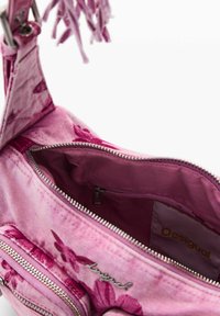 Rosa skuldertaske med blomsterprint og sølvfarvede lynlåse, åbent hovedrum med indvendig lynlåslomme og Desigual mærke.