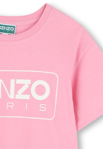 T-shirt en coton rose avec des manches courtes, un col rond et un grand logo blanc "KENZO PARIS" dans un contour rectangulaire sur le devant.