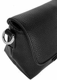 Czarna skórzana torebka o fakturowanym wykończeniu, z zapięciem na klapkę i srebrnym detalem w postaci pierścienia po boku. Prostokątny kształt z przeszytymi brzegami.