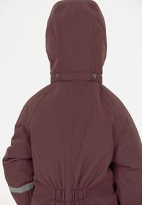 Bordeaux-rode capuchonjack met elastische taille, drukknoopsluiting en reflecterende strepen op de mouwen. Glad, waterafstotend materiaal. Achteraanzicht.