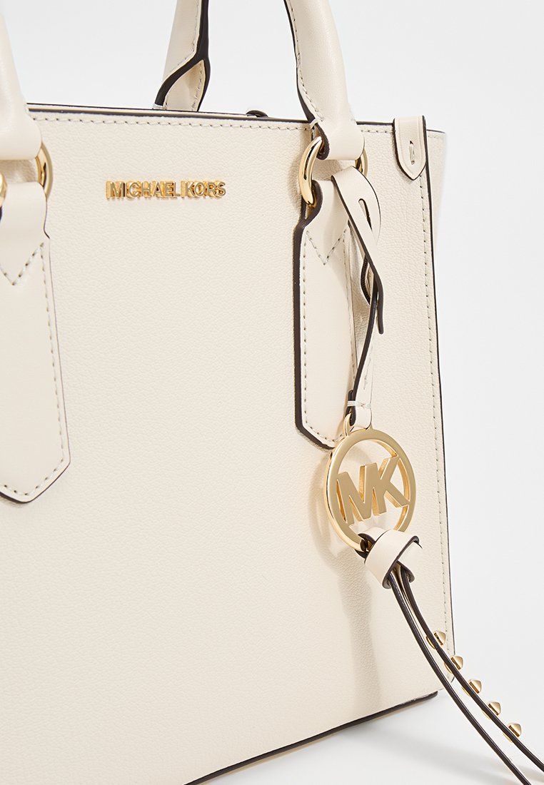 Cremfarbene Lederhandtasche mit goldfarbenen Beschlägen. Einschließlich eines abnehmbaren Etiketts mit "MK"-Logo und kontrastierendem dunklen Riemen. Strukturierte Form und elegante Nähte.