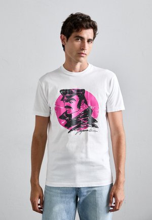 White cotton t-shirt featuring a black and pink graphic print of a man in profile, wearing a hat, with signature detail. Short sleeves.