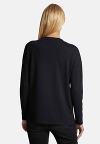 Zwarte lange mouwen trui met een relaxed fit, ronde halslijn en een gladde textuur, van achteren weergegeven tegen een effen achtergrond.