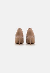 Nude högklackade skor med spetsig tå, slät läderöverdel, genomskinlig stilettklack och minimal sömnadsdetalj.
