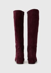 Bordeaux suède knie-laarzen met een ronde neus, stevige blokhak en een rits aan de zijkant voor gemakkelijk aan- en uittrekken. Glad textuur met minimale accenten.