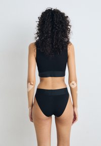 Brasiera sport neagră și slip de bikini cu talie înaltă dintr-un material neted și elastic. Prezintă un design fără cusături, cu o talie lată și un stil minimalist.