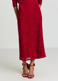 Roter Spitzen-Midirock mit floralem Muster, tailliert und zum Saum hin ausgestellt, kombiniert mit roten Riemchenabsätzen.