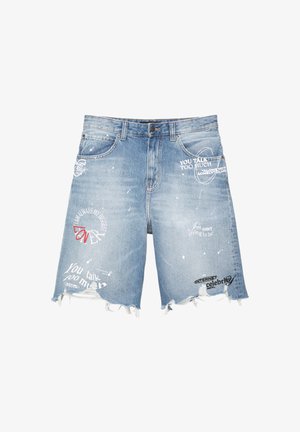 Lyseblå denim shorts med slidser i kanterne, med trykt tekst og grafik i hvidt og rødt, herunder forskellige sætninger og logoer.