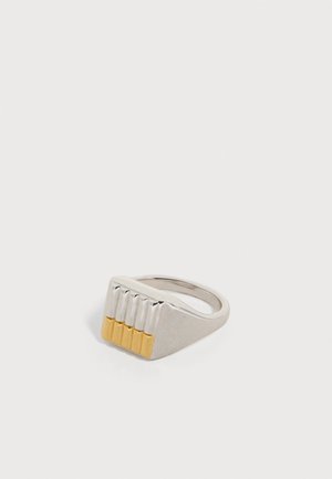 Anello chevalier in argento con una parte superiore rettangolare caratterizzata da cinque scanalature verticali, ciascuna terminante con un piccolo dettaglio in oro.