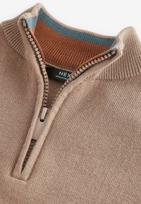 Beige dragkedjeströja med ribbad krage och orangea samt blå accenter. Slät stickad textur och lätt material.