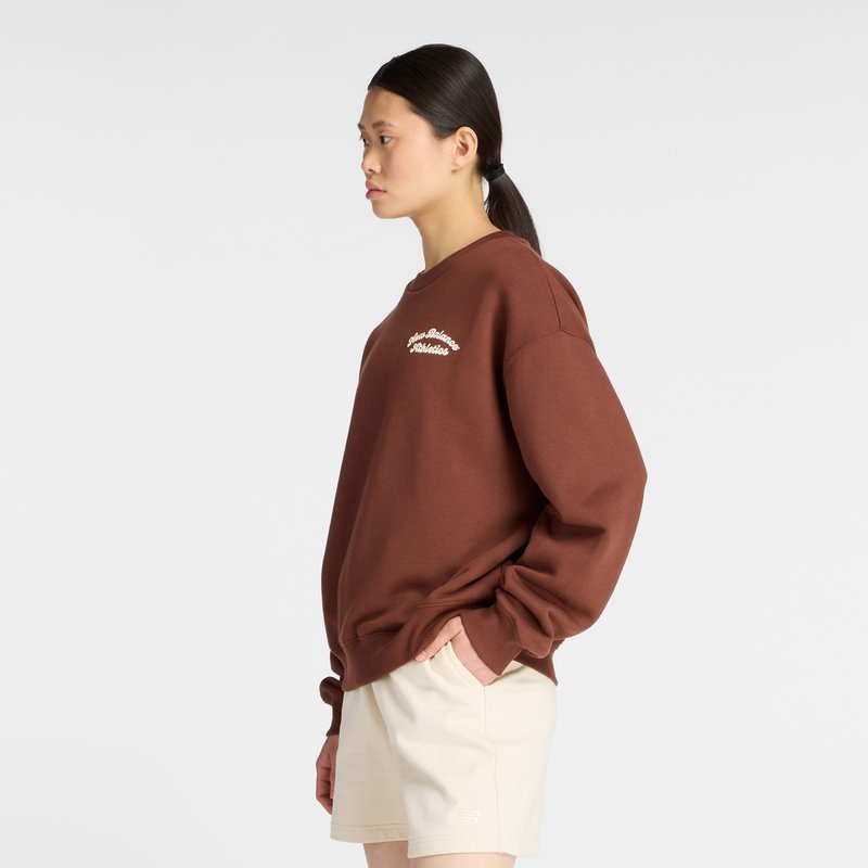Brauner Rundhals-Sweatshirt mit gesticktem Text, kombiniert mit hellbeigen Shorts. Lockere Passform mit überschnittenen Schultern und Rippbündchen.