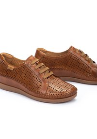 Zapatillas de cuero marrón perforado con punta redondeada, diseño de cordones, costuras en contraste y suela de goma flexible.