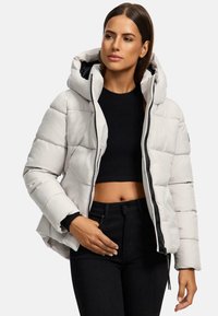 Veste rembourrée gris clair avec capuche, dotée d'une fermeture éclair à l'avant et de poignets élastiques. Associée à un haut noir court et à un pantalon taille haute.