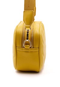Borsa a tracolla in pelle gialla trapuntata con chiusura a zip, tracolla piatta e hardware metallico. Forma arrotondata con una superficie liscia.