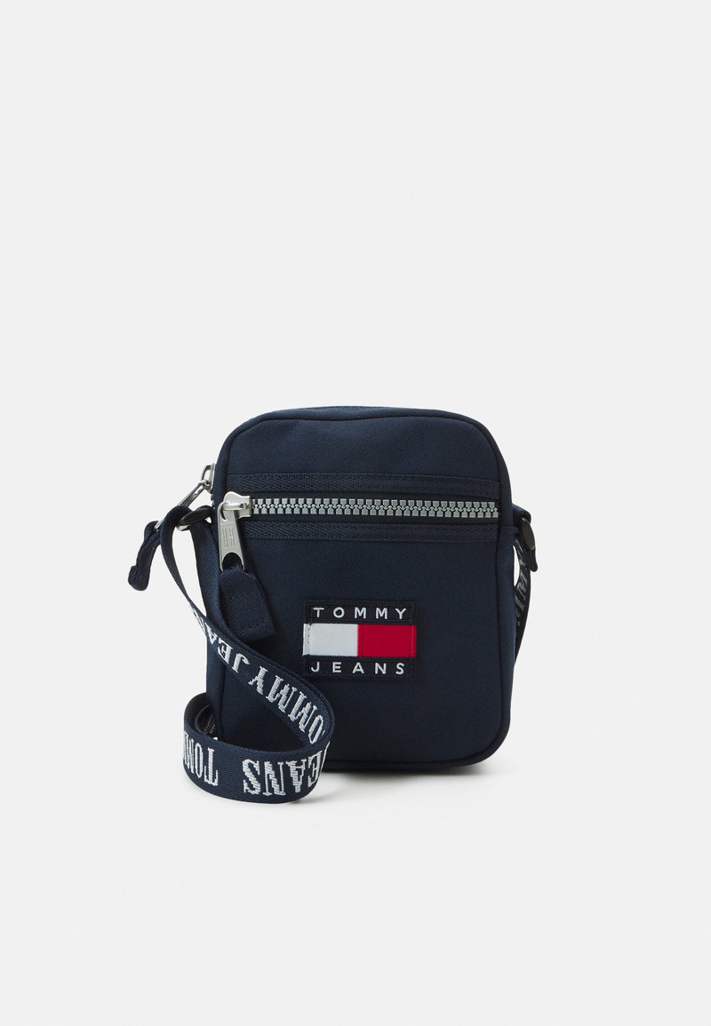 Borsa a tracolla navy realizzata in tessuto, con zip argentata, tracolla regolabile e toppe con logo in rosso e bianco. Forma quadrata compatta.