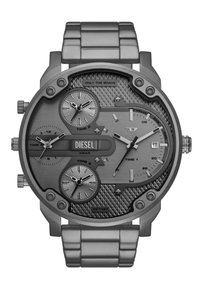 Montre en acier inoxydable gris avec plusieurs cadrans, motif texturé sur le cadran et accents numériques. Présente le logo "DIESEL" et un affichage de la date.