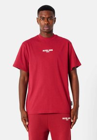 Rode katoenen T-shirt met korte mouwen en ronde hals. Bevat witte geprinte tekst "SIXTH JUNE PARIS" op de borst. Rechte zoom.