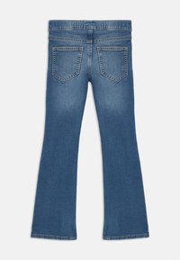 Blaue Jeans aus Denim mit Gesäßtaschen und ausgestellt geschnittenen Beinen, flach ausgelegt und die Rückseite zeigend.