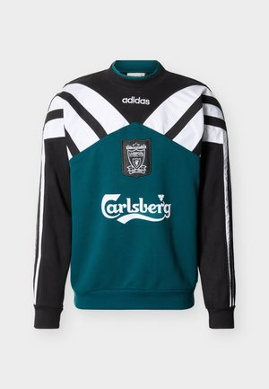 Pika varrukaga petrolisinine, musta ja valgega Adidas dressipluus, millel on ees Liverpooli FC vapp ja Carlsbergi logo.