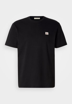 T-shirt di cotone nero con maniche corte, collo rotondo e un piccolo logo ricamato sul lato sinistro del petto. Texture liscia, vestibilità regolare.