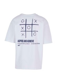 White cotton t-shirt featuring a navy tic-tac-toe graphic on the back, with the text "ASPIRE AND ACHIEVE" below. Short sleeves, loose fit.