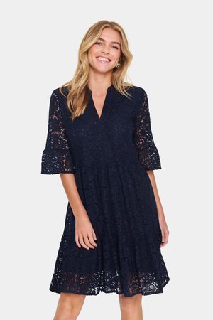 Robe en dentelle bleu marine avec une jupe évasée, décolleté en V et manches jusqu'au coude ornées de volants et de motifs floraux.