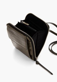 Obdélníková crossbody taška v olivově zelené, s raženou krokodýlí texturou. Zipové zavírání, několik vnitřních kapes, nastavitelné ramenní popruhy. Černá podšívka.