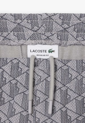 Grau melierte Jogginghosen aus Stoff mit einem geometrischen Muster, elastischem Bund mit Kordelzug und einem Etikett mit der Aufschrift „LACOSTE REGULAR FIT“.