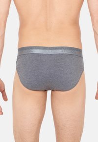 Graue Baumwollslips mit einem silbernen Bund, der Logo-Details aufweist, eng anliegendem Schnitt und glatter Textur. Die Rückseite zeigt ein schlichtes, körperbetontes Design.