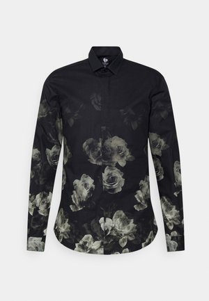 Chemise noire à manches longues avec boutons, ornée d'un motif floral de roses blanches décolorées sur le devant, les manches et l'ourlet inférieur.