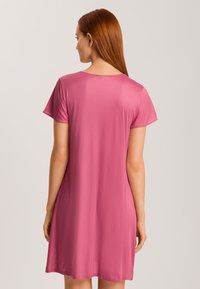 Rosa kortärmad klänning med ett mjukt, lätt tyg som faller strax över knäet, med rund halsringning och en avslappnad passform.