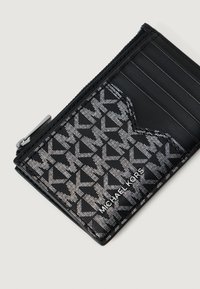 Čierny držiteľ karty Michael Kors s bielym vzorom loga MK, predná vrecko, viaceré priehradky na karty a malý zipsový oddiel.