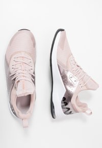 Baskets de sport rose clair avec tige en mesh, accents réfléchissants, semelle rembourrée et une languette à l'arrière. Semelle extérieure noire avec texture.