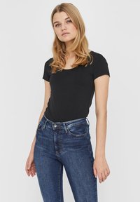Sort kortærmet t-shirt med rund hals, sammen med mørkeblå denim jeans med et klassisk fem-lomme design og subtile slidte effekter.