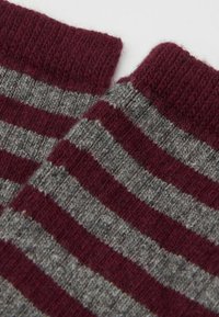 Røde og grå stribede strikstrømper med ribbet tekstur, der har vekslende brede og smalle striber samt et blødt uldblandingsmateriale.