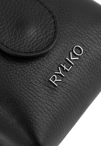 Borsa in pelle nera con una superficie testurizzata, dotata di un pattina arrotondata e di un logo metallico "RYŁKO" in argento sulla parte frontale.