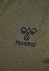 Svart hummelbi-logotyp tryckt på olivgrön texturerad tyg, centrerad i bilden.