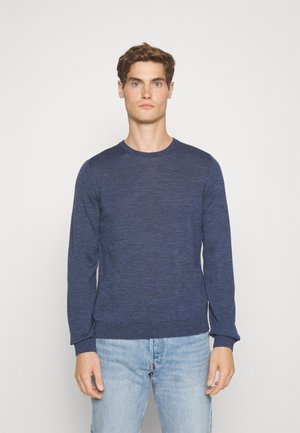 Maglione a maniche lunghe blu navy con collo a giro, realizzato in tessuto testurizzato, presenta polsini e orlo a costine, indossato con jeans azzurri.