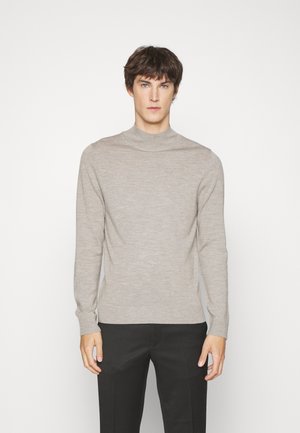 Hellgrauer, gerippter Rollkragenpullover aus weichem Material, mit langen Ärmeln und taillierter Passform. Zusammen mit dunklen Hosen getragen.
